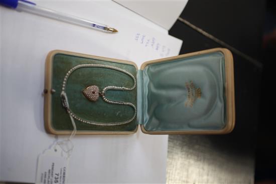 An early 20th century gold, ruby and split pearl set heart shaped pendant locket, pendant inc. bale 1in.